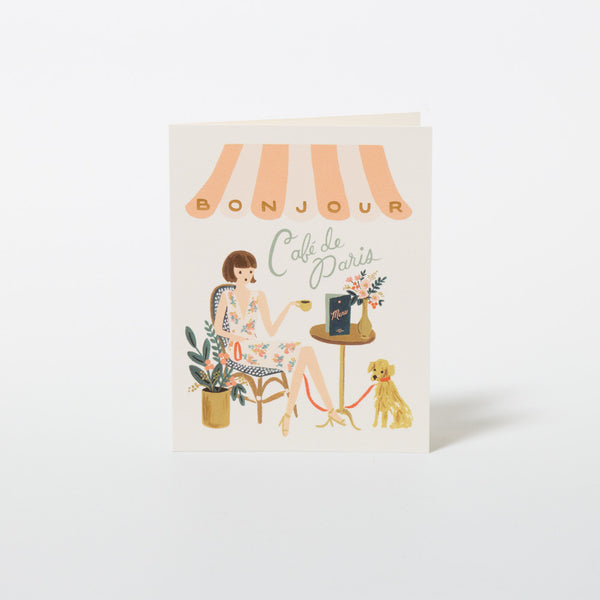 Grußkarte "Bonjour" von Rifle Paper Co. mit Dame und Hund im Pariser Straßencafé.