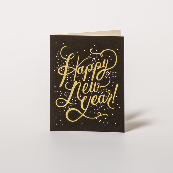 Glückwunschkarte zu Neujahr mit goldener Schrift auf schwarzem Grund von Rifle Paper Co.